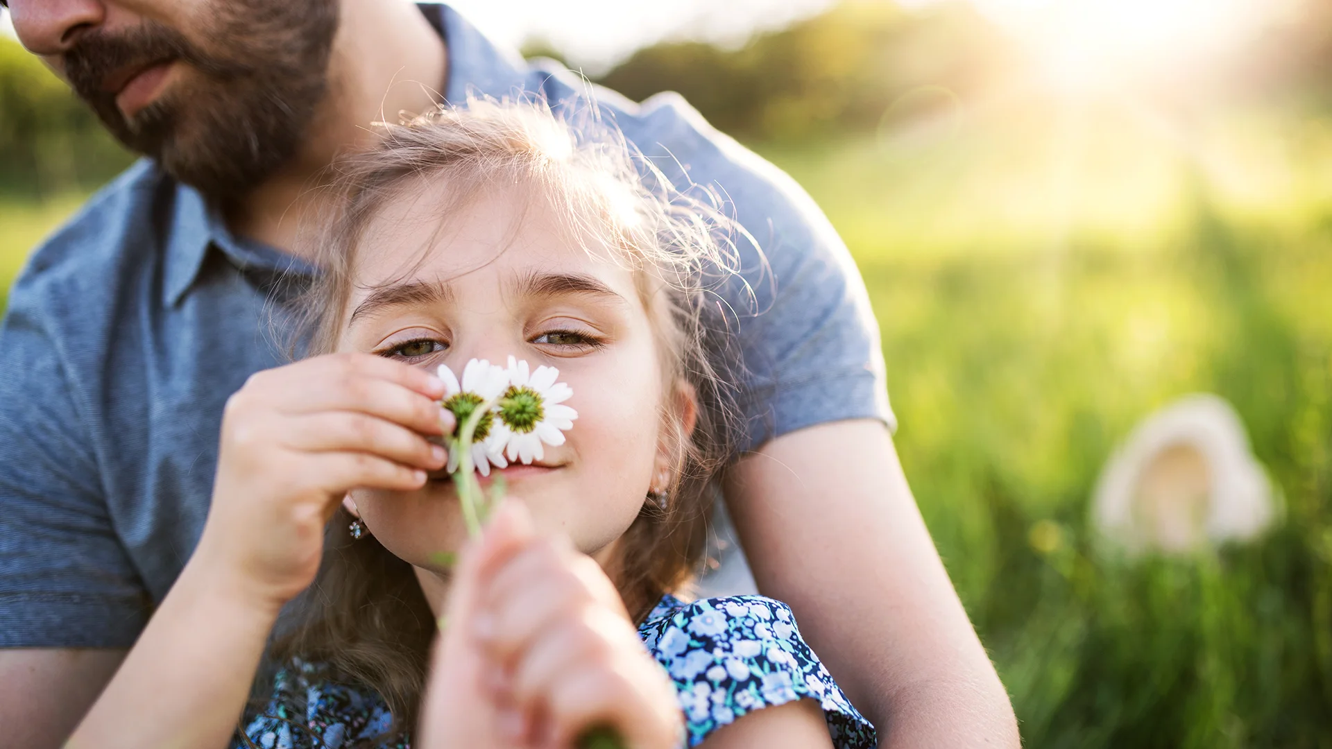 Vater und Kind mit Gänseblümchen vor Gesicht